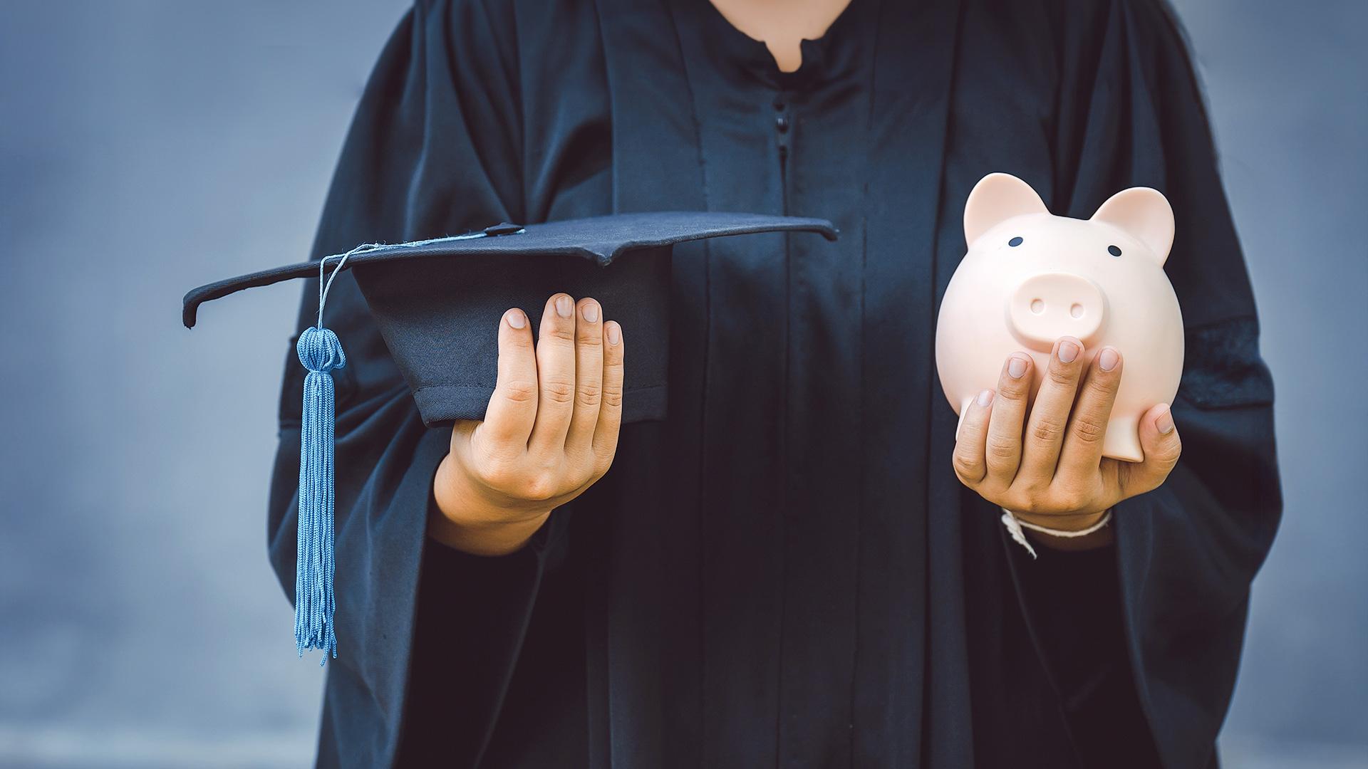 Student holding mortarboard and piggy bank
