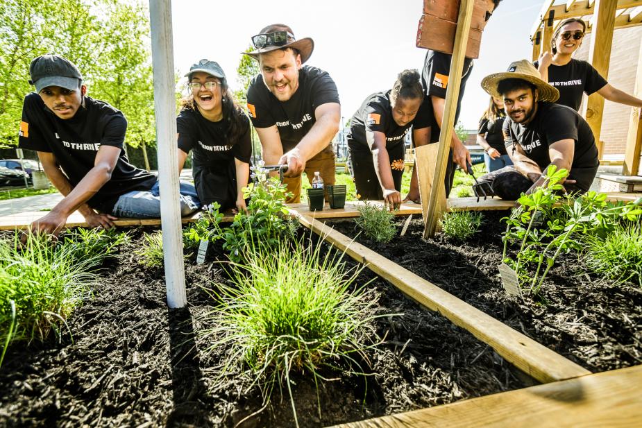 Group of seven students hover over raised garden beds. 