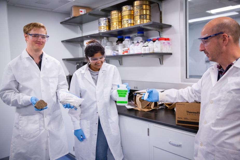 Students in lab coats working with their professor