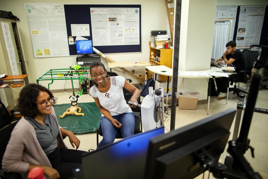 Students laughing looking at a computer together in a research lab