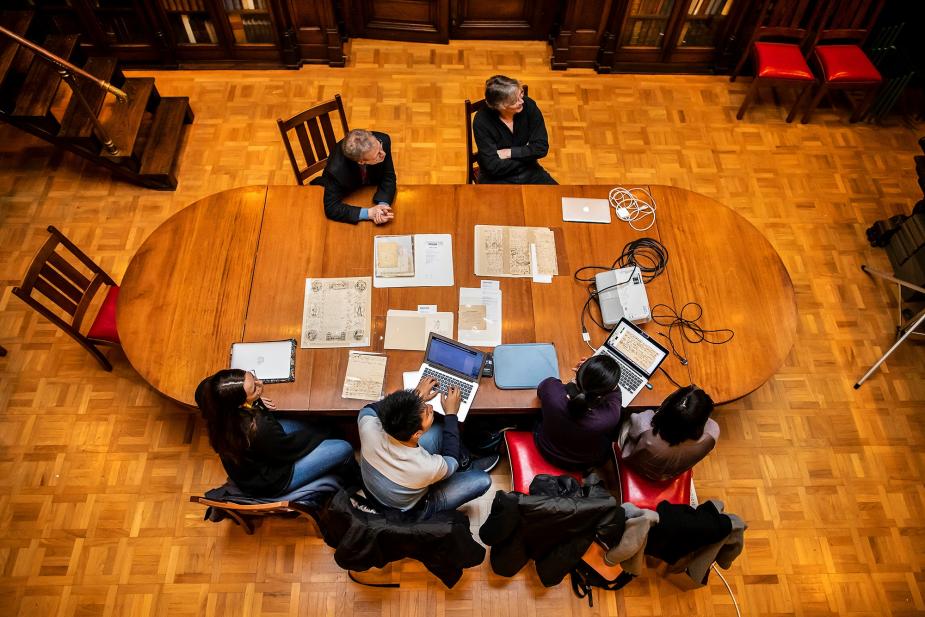 Overhead view of students in the library at a table covered in rare manuscripts