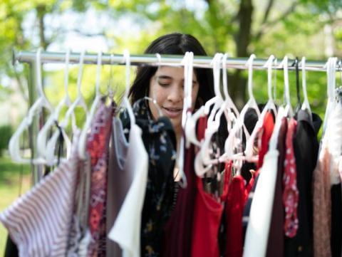 Student looking through thrifted clothing