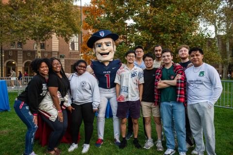 A group of students poses with the Quaker mascot