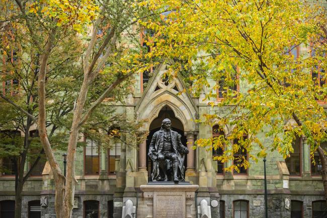 Ben Franklin statue in front of College Hall with Fall foliage
