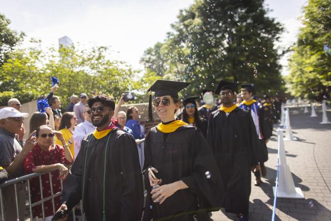 Smiling students walking at graduation with bubbles in the air