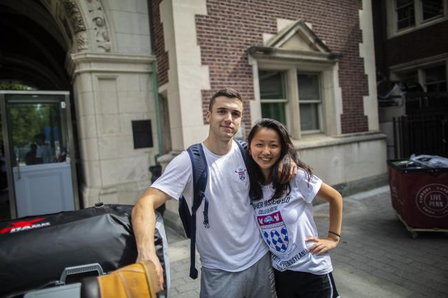 Two international students pose together in front of a Penn dorm during move-in. 