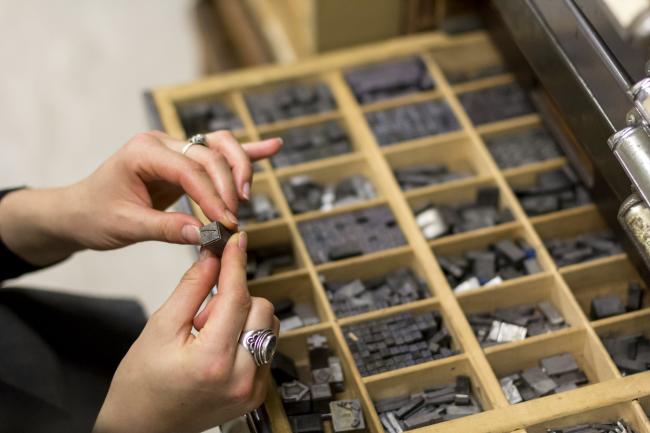 There is a large drawer open with multiple compartments of miscellaneous parts. A hand is holding a small part to examine. 