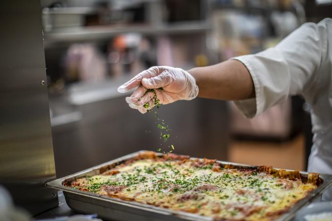 Baked dish being seasoned with additional greens