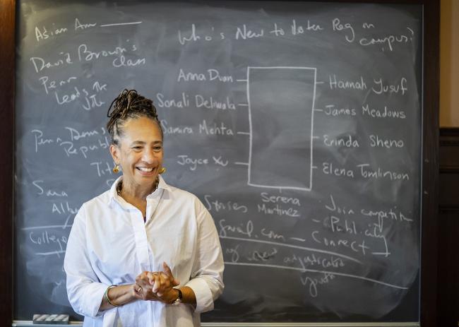 Professor smiling in front of a chalkboard