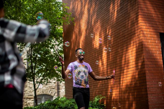 Person playing with bubbles and smiling outside of the LGBT center