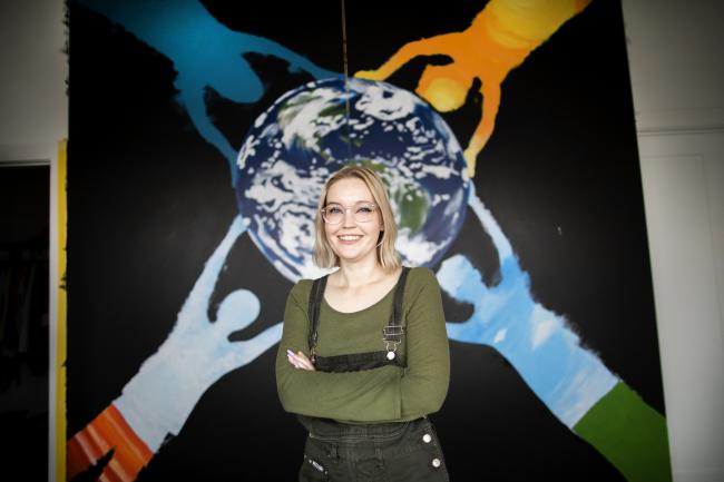 Student in front of mural with image of the earth