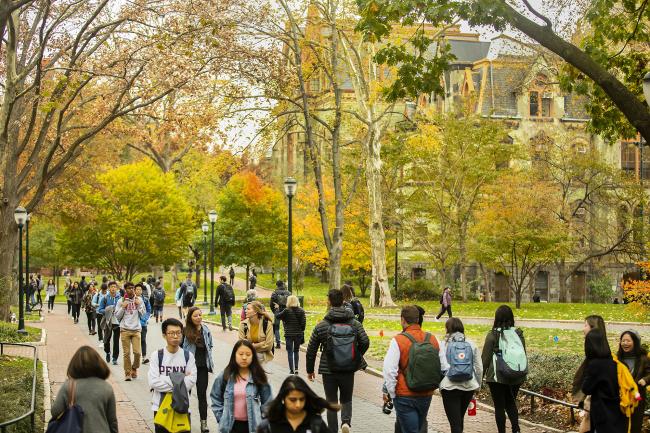 Student's walking along Penn's campus with fall foliage