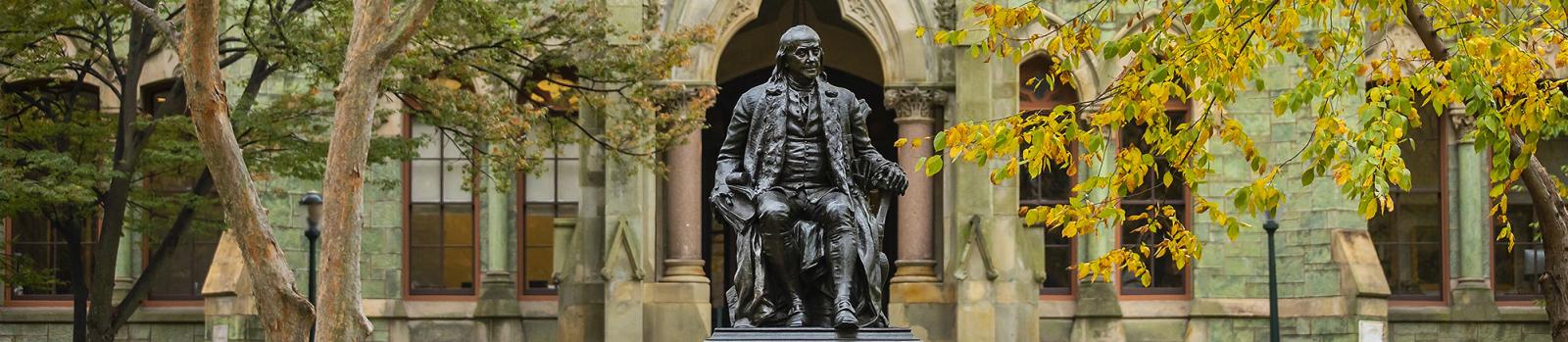 Ben Franklin statue in front of College Hall with Fall foliage