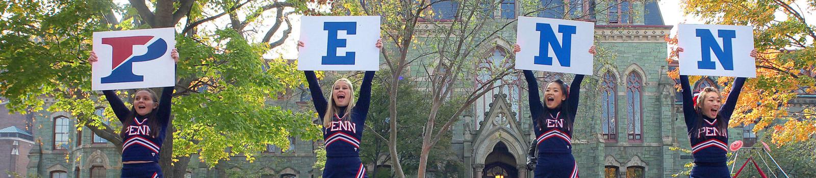 Cheerleaders holding signs to spell PENN