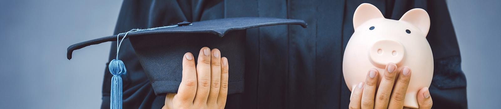 Graduate holding piggy bank