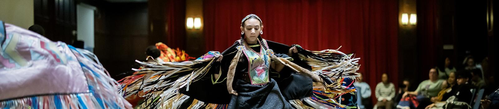 Young woman dances in the center of a powwow.