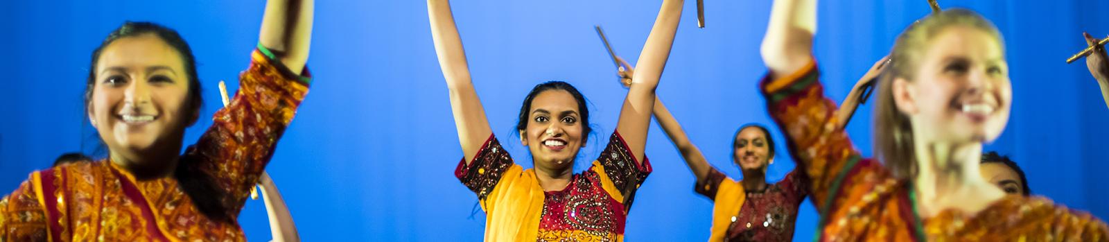 Group of four Penn students are dancing on stage in sarees.