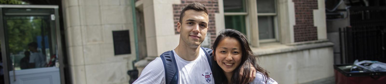 Two international students pose together in front of a Penn dorm during move-in. 