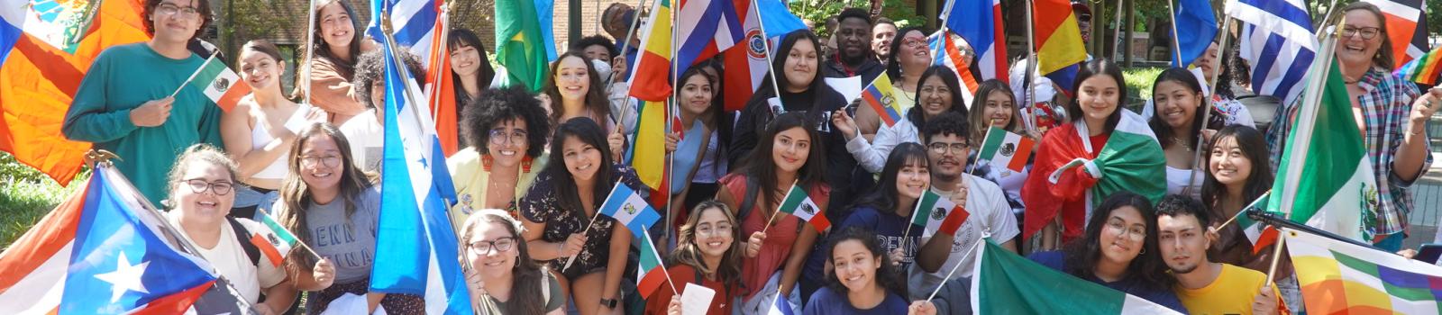 Large group of Casa Latina students and staff stand outside holding flags from Latin America.