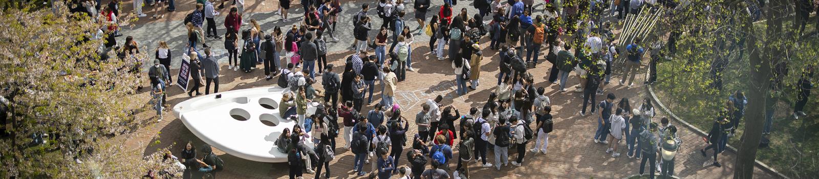 Large group of Penn students gather by the ‘Split Button’ statue on Penn campus. 