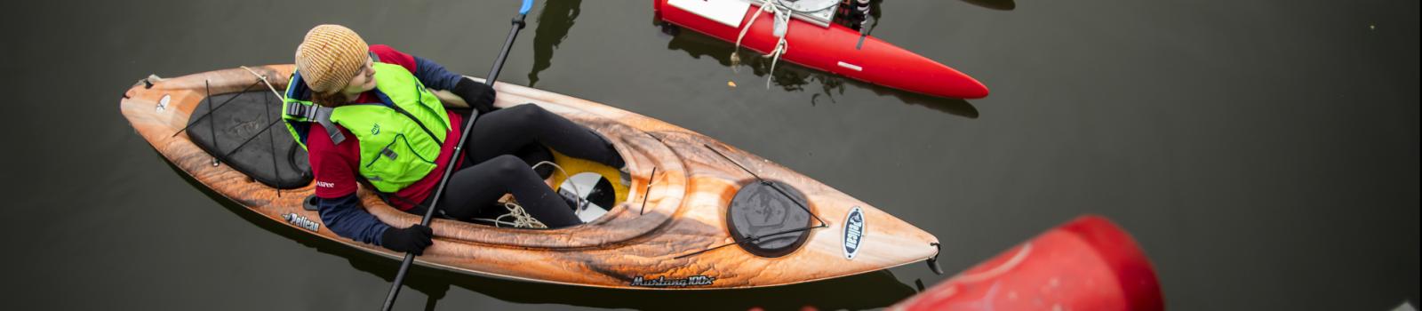 Student in kayak  deploying aquatic research