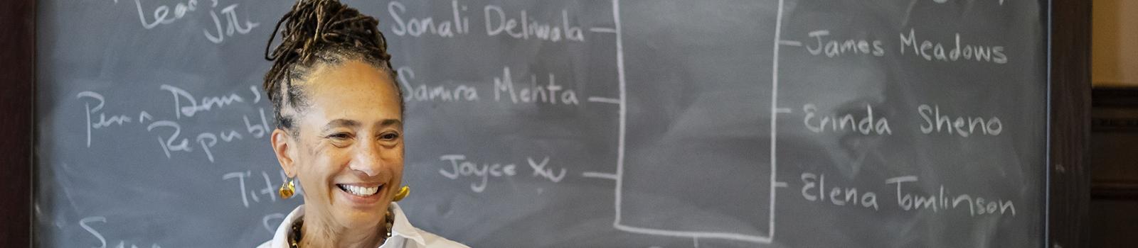 Professor smiling in front of a chalkboard
