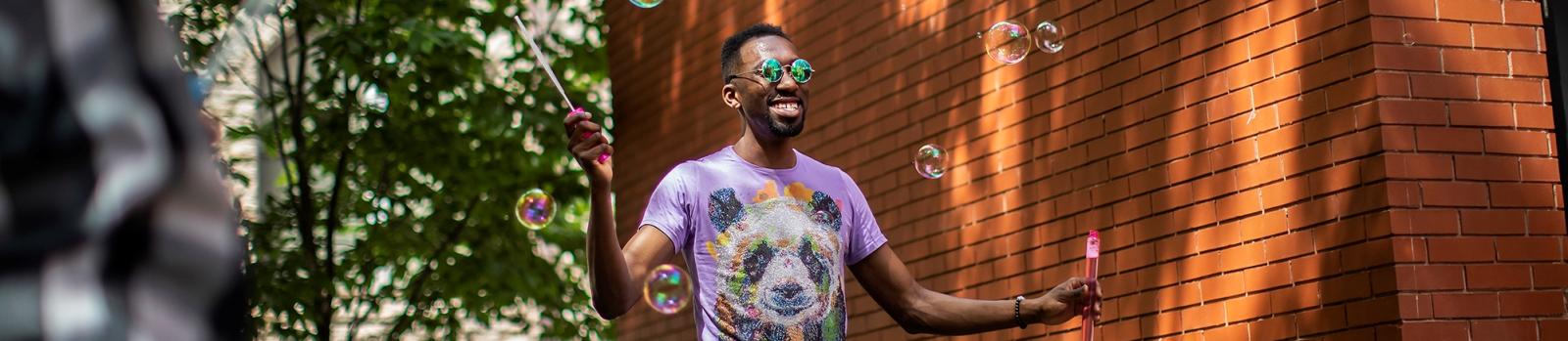 Person playing with bubbles and smiling outside of the LGBT center