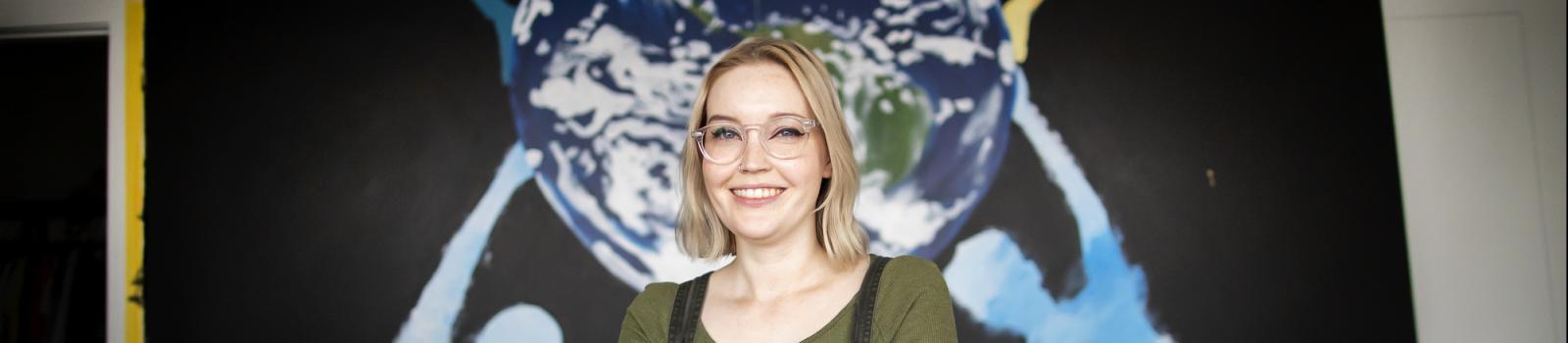 Student in front of mural with image of the earth
