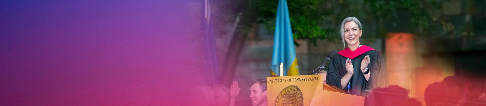 Dean Soule applauding at a podium during convocation