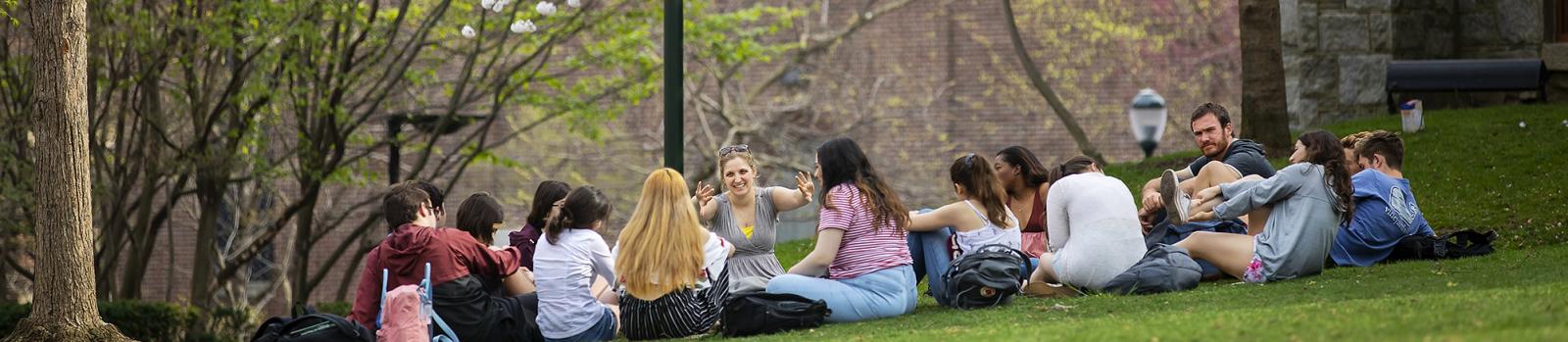 Students sitting in a circle on the lawn under a blooming Cherry tree
