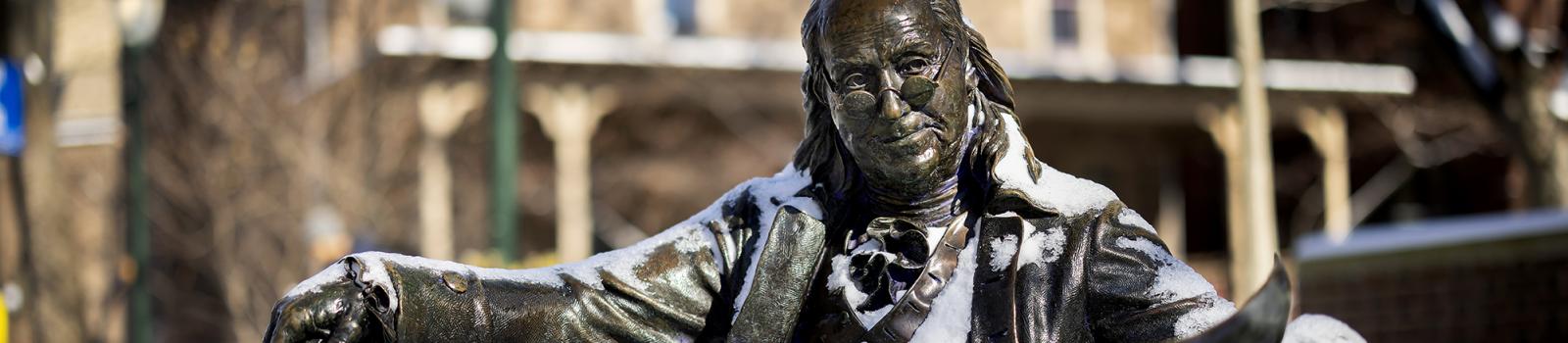 Sculpture of Benjamin Franklin dusted with snow.